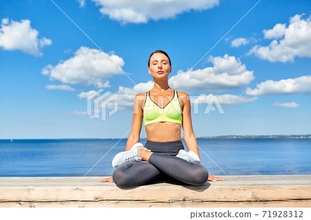 young woman meditating in lotus pose at seaside young woman meditating in lotus pose at seaside 71928312