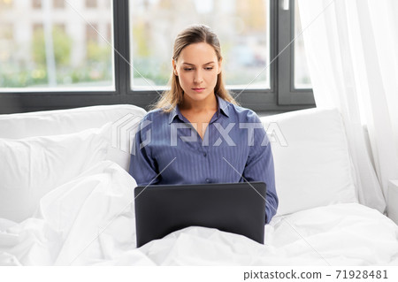 young woman with laptop in bed at home bedroom 71928481