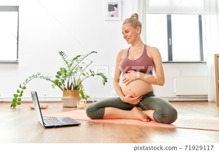 pregnant woman with laptop doing yoga at home 71929117