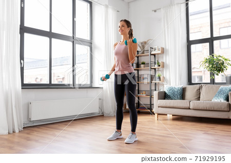 smiling young with dumbbells exercising at home 71929195