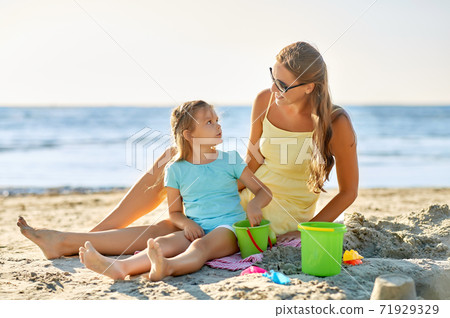 mother and daughter playing with toys on beach mother and daughter playing with toys on beach 71929329