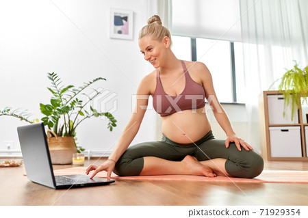 pregnant woman with laptop doing yoga at home pregnant woman with laptop doing yoga at home 71929354