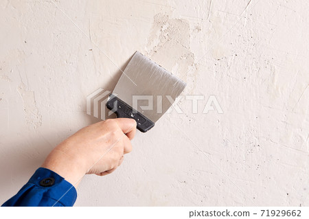 Applying skim plaster to wall with help of putty knife. Applying skim plaster to wall with help of putty knife. 71929662