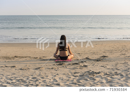 European woman doing yoga on the sandy beach of Palolem in Goa, India 71930384