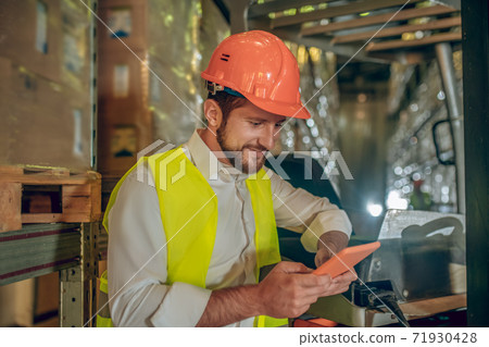 Young bearded worker watching something on the tablet Young bearded worker watching something on the tablet 71930428