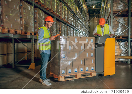 Male warehouse workers in helmets standing near containers Male warehouse workers in helmets standing near containers 71930439
