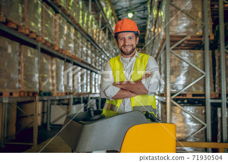 Warehouse worker in orange helmet looking contented 71930504