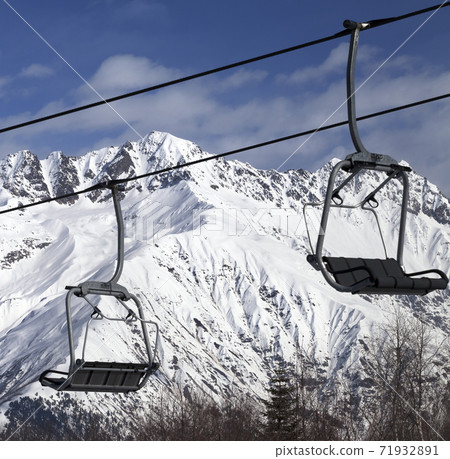 Chair-lift on ski resort and snowy mountains at cold sunny day Chair-lift on ski resort and snowy mountains at cold sunny day 71932891