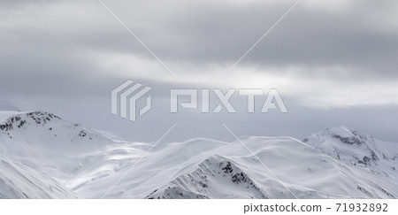 Sunlight snowy mountains in fog and gray overcast sky Sunlight snowy mountains in fog and gray overcast sky 71932892