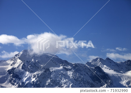 Snowy mountains with glacier and cloudy blue sky at sunny evening Snowy mountains with glacier and cloudy blue sky at sunny evening 71932990