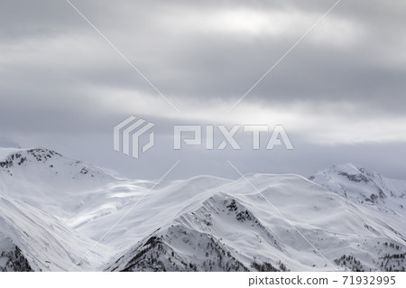 Sunlight snowy mountains in fog and gray overcast sky Sunlight snowy mountains in fog and gray overcast sky 71932995