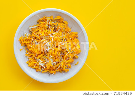 Petals of marigold flower on yellow background. Petals of marigold flower on yellow background. 71934459