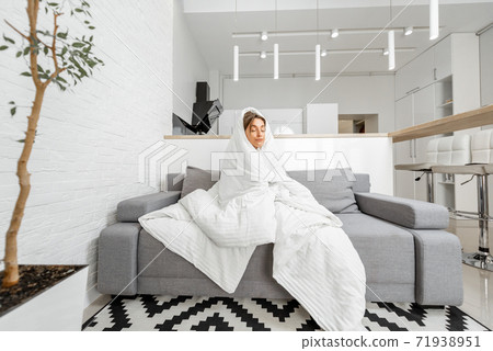 Woman covered with a blanket on the couch at home Woman covered with a blanket on the couch at home 71938951