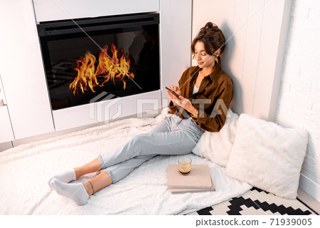 Woman relaxing near the fireplace at home 71939005