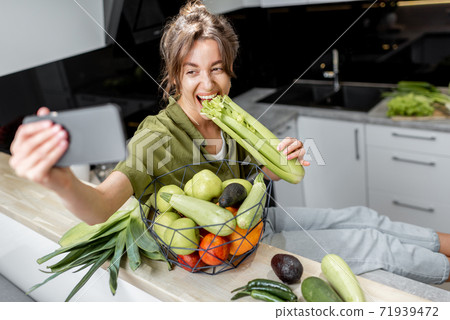 Woman with healthy food and phone on the kitchen at home 71939472