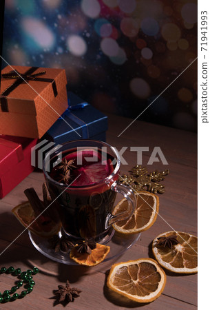 Glass Cup of fragrant mulled wine with spices, decorations for the new year branches and gifts. Vertical orientation 71941993