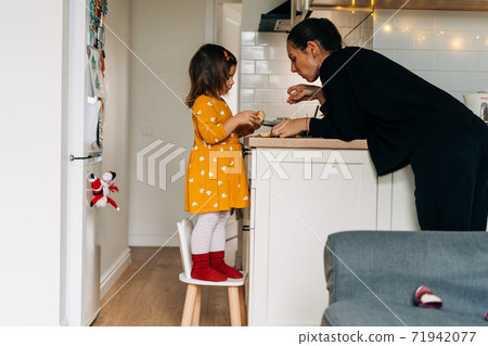 Caucasian girl peeling tangerines on kitchen counter. Healthy child diet. Immune boosting with Caucasian girl peeling tangerines on kitchen counter. Healthy child diet. Immune boosting with 71942077