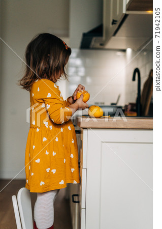Caucasian girl peeling tangerines on kitchen counter. Healthy child diet. Immune boosting with Caucasian girl peeling tangerines on kitchen counter. Healthy child diet. Immune boosting with 71942105