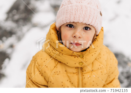 Close up portrait of caucasian toddler girl with red cheeks on winter day.  71942135