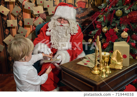 Boy with Cochlear Implants Seal Letter To Santa Claus For New Year 71944038