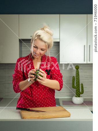 blonde vegan woman cuts avocado in kitchen blonde vegan woman cuts avocado in kitchen 71946000