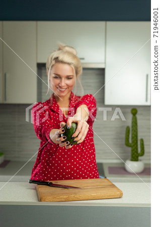 blonde vegan woman cuts avocado in kitchen blonde vegan woman cuts avocado in kitchen 71946001
