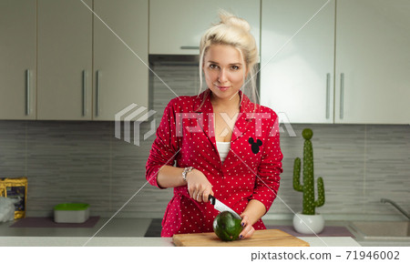 blonde vegan woman cuts avocado in kitchen blonde vegan woman cuts avocado in kitchen 71946002