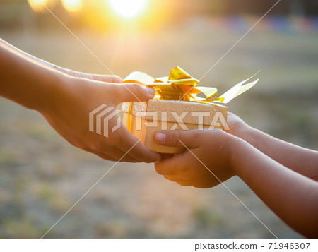 A boy and a kid are holding a gift box 71946307