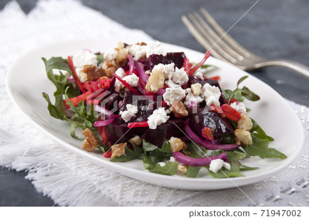 Salad in a white plate on a white napkin on a gray table 71947002