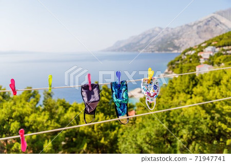 Fabric masks hanging on the clothesline on the sea background. Coronavirus concept. Fabric masks hanging on the clothesline on the sea background. Coronavirus concept. 71947741