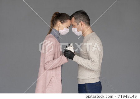 happy couple in love in repsiratory masks and gloves hugging each other isolated on grey 71948149