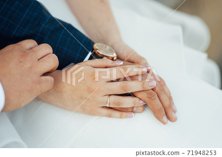 close-up portrait of the bride and groom. They hug their arms. Wedding rings on their hands 71948253