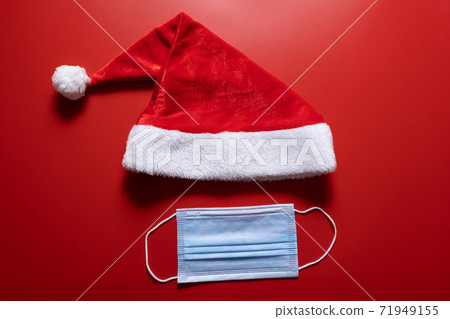 Santa claus hat and medical mask on a red background. Santa claus hat and medical mask on a red background. 71949155