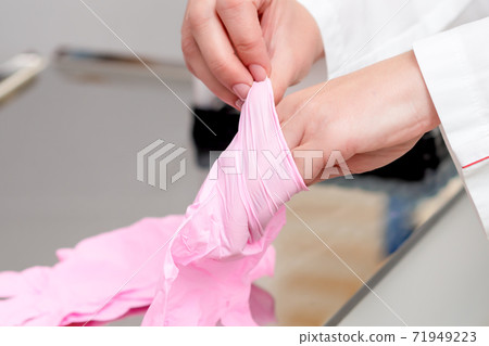 Doctor puts on gloves. 71949223