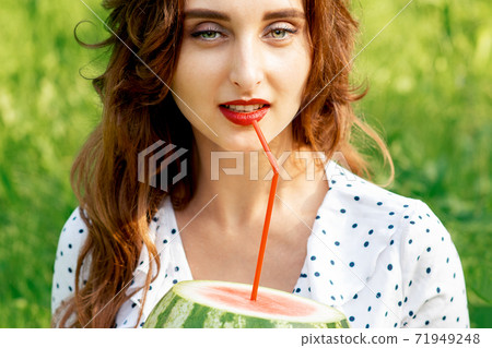 Woman holds watermelon on grass. Woman holds watermelon on grass. 71949248