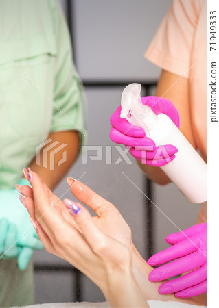 Beautician disinfects hands with antiseptic spray Beautician disinfects hands with antiseptic spray 71949333