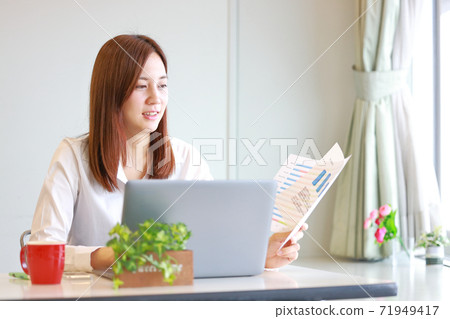A woman teleworking while looking at materials A woman teleworking while looking at materials 71949417