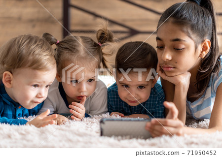 friendship, childhood, technology concepts - 4 young children baby of different nationalities Persian and Slavic appearance watch cartoon on smartphone on bed. kids preschool speak by video conference friendship, childhood, technology concepts - 4 young children baby of different nationalities Persian and Slavic appearance watch cartoon on smartphone on bed. kids preschool speak by video conference 71950452