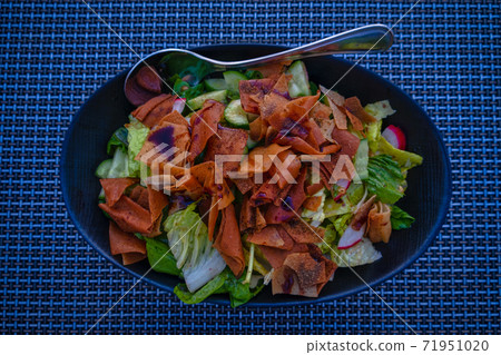 Fattoush (Lebanese salad) close up image in a blue plate . It is made with vegetables and crispy toasted flatbread, which soaks up the dressing beautifully. Fattoush (Lebanese salad) close up image in a blue plate . It is made with vegetables and crispy toasted flatbread, which soaks up the dressing beautifully. 71951020