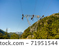Power lines and tower passing through mountains. 71951544