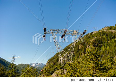 Power lines and tower passing through mountains. 71951544