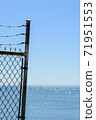 Edge of fence and barb wire against sky and water. 71951553
