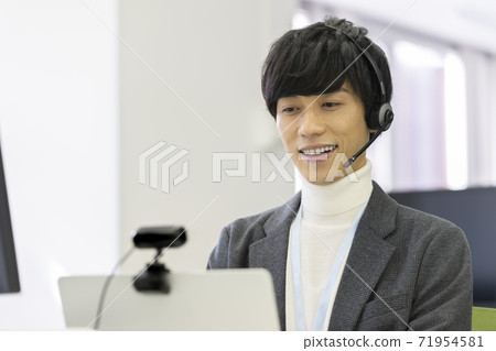 一名男子戴著耳機,前往帶有網絡攝像頭的計算機 一名男子戴著耳機,前往帶有網絡攝像頭的計算機 71954581