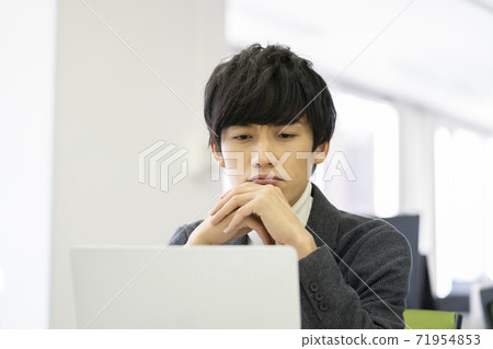 A man frowning while looking at a computer screen 71954853