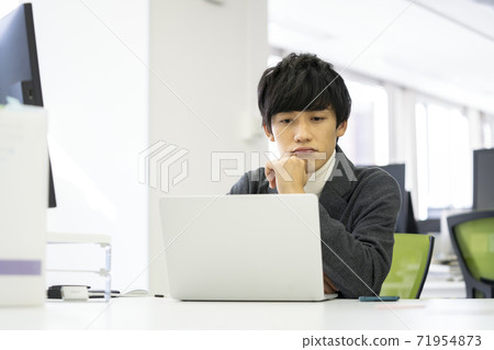 A man frowning while looking at a computer screen 71954873