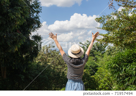 Asian woman wear weave hat and stand on wooden terrace. She feeling relax and happiness. Asian woman wear weave hat and stand on wooden terrace. She feeling relax and happiness. 71957494
