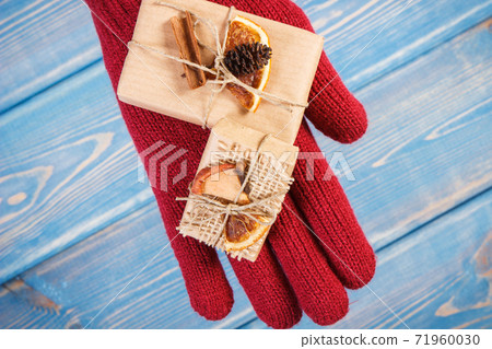Hand of woman in gloves with decorated gifts for Christmas or other celebration 71960030