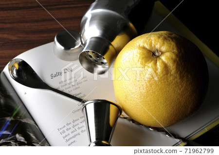 Make a cocktail with a shaker while looking at a cocktail book Make a cocktail with a shaker while looking at a cocktail book 71962799