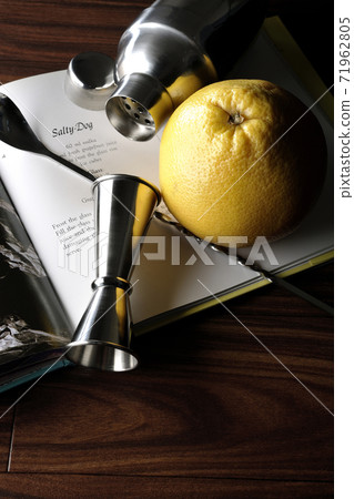 Make a cocktail with a shaker while looking at a cocktail book Make a cocktail with a shaker while looking at a cocktail book 71962805