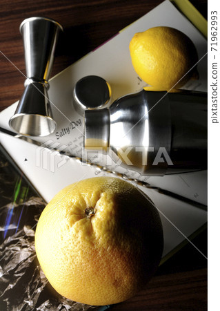 Make a cocktail with a shaker while looking at a cocktail book using grapefruit and lemon Make a cocktail with a shaker while looking at a cocktail book using grapefruit and lemon 71962993